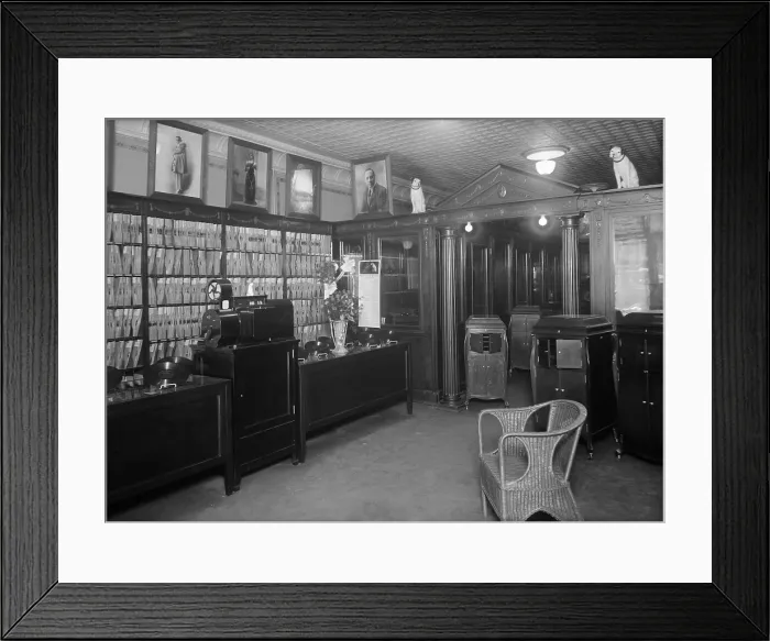 Framed Print : Waldman's Record Shop in New York City ca. 1915-20. The store displays Victrolas, hand cranked record players in wood cabinets which played 78 RPM phonographs