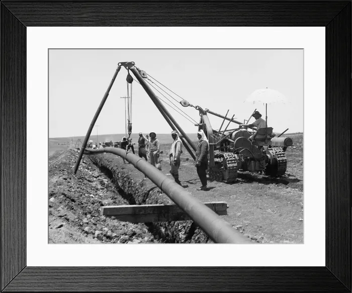 Framed Print : Dropping a welded pipe into a trench with a crane while laying the Iraq Petroleum Company's pipe line across Palestine's Plain of Esdraelon, July 1933