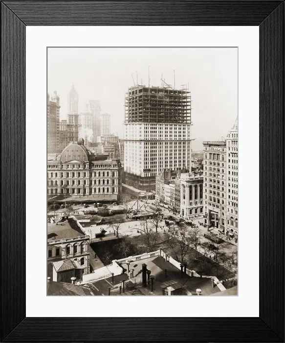 Framed Print : Woolworth Building, partially-constructed building amidst smaller buildings. The lower floors have received a white terra-cotta facing worked in lacy Gothic style