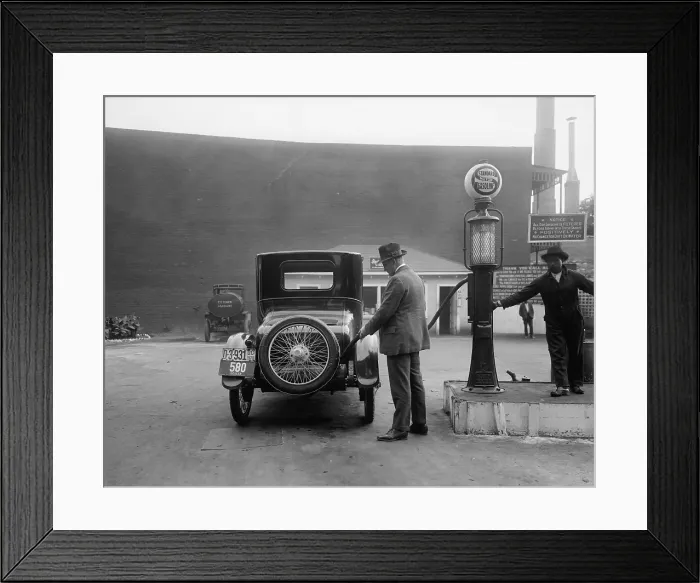 Framed Print : Man fueling his car at a self-service Standard Motor gas station in Washington D.C. area. A sign tells customers the gasoline is filter and contains no dirt or water. 1920
