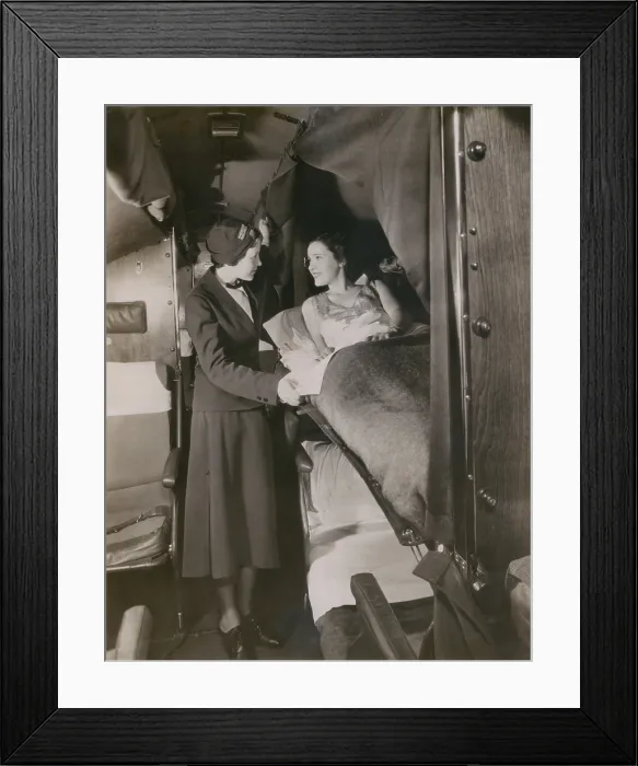 Framed Print : American Airlines stewardess with a passenger in a sleeping berth on a commercial flight in the 1930s. American Airlines began using stewardesses in 1933 Framed Print : American Airlines stewardess with a passenger in a sleeping berth on a commercial flight in the 1930s. American Airlines began using stewardesses in 1933