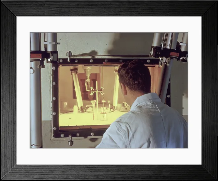 Framed Print : Nuclear engineer is protected from radiation by a fifty-two inch thick, oil-filled glass window as he examines irradiated materials Framed Print : Nuclear engineer is protected from radiation by a fifty-two inch thick, oil-filled glass window as he examines irradiated materials