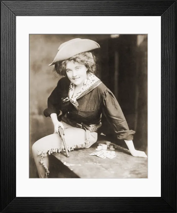 Framed Print : Turn of the century Cowgirl holding revolver, seated on a table, with playing cards and chips. Ca. 1900 Framed Print : Turn of the century Cowgirl holding revolver, seated on a table, with playing cards and chips. Ca. 1900