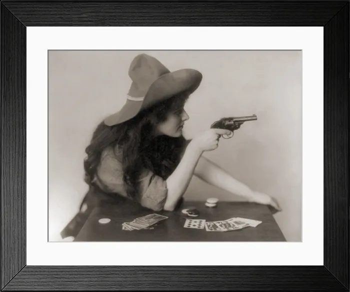 Framed Print : Cowgirl with deck of cards and chips, pointing a pistol. 1912