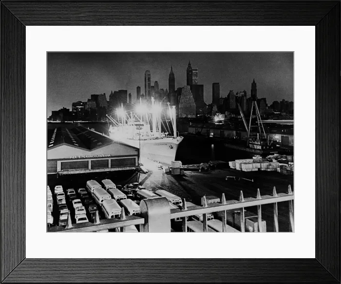 Framed Print : New York City's Manhattan's skyline shrouded in darkness, is offset by the lights of a freighter at a Brooklyn pier Framed Print : New York City's Manhattan's skyline shrouded in darkness, is offset by the lights of a freighter at a Brooklyn pier