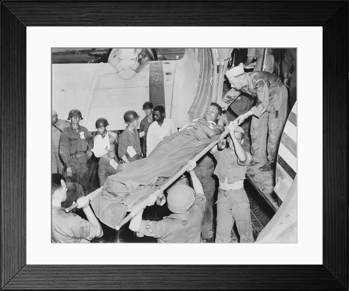 Framed Print : U.S. soldier is lifted from a Air Force C-47 in Japan from an airstrip near the battle front in Korea. Other wounded soldiers stand by the plane's wing