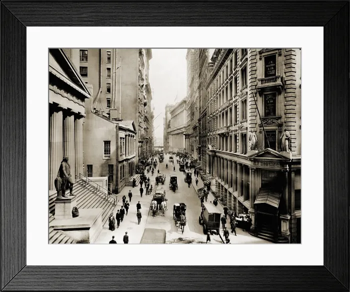 Framed Print : New York City's Wall Street, looking east from the intersection with Broad Street. In foreground left is Federal Hall; on right is J.P. Morgan's bank Framed Print : New York City's Wall Street, looking east from the intersection with Broad Street. In foreground left is Federal Hall; on right is J.P. Morgan's bank