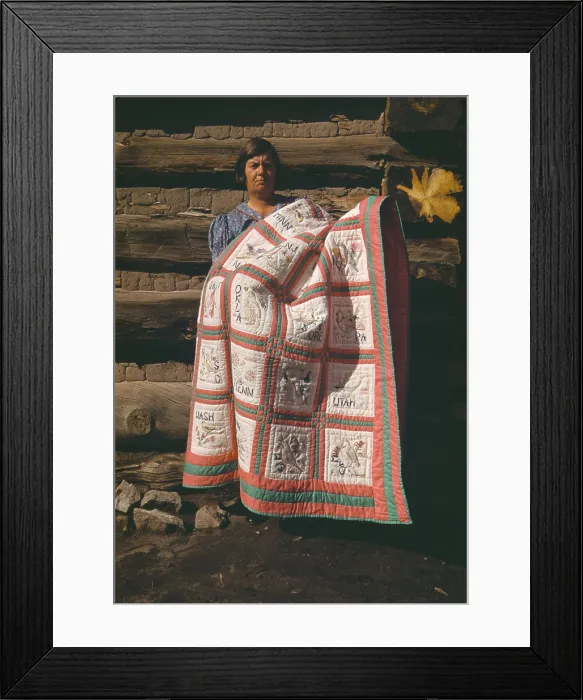 Framed Print : Mrs. Bill Stagg displays her state quilt in front of her log home in Pie Town New Mexico. The quilt had embroidered panes of each of the 48 US States. Oct. 1940