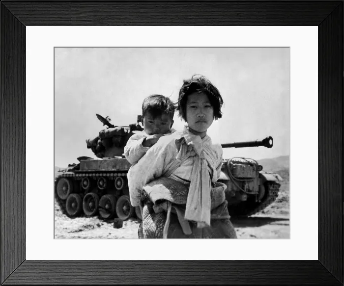 Framed Print : With her brother on her back, a war weary Korean girl tiredly trudges by a stalled M-26 tank, at Haengju, Korea. June 9, 1951. Korean War, 1950-53. (BSLOC_2014_11_248)