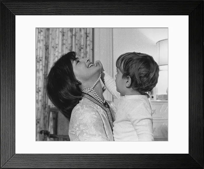 Framed Print : First Lady Jacqueline Kennedy laughs as her son John Kennedy Jr. plays with her simulated-pearl necklace in White House nursery. Nov. 27, 1962