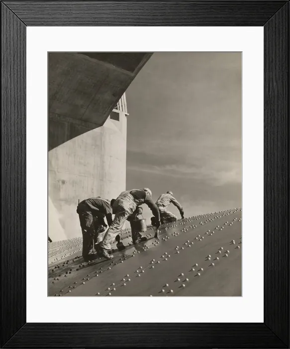 Framed Print : Three workers painting on a slanted wall of riveted-steel plates on the Hoover Dam spillway. Ca. 1940