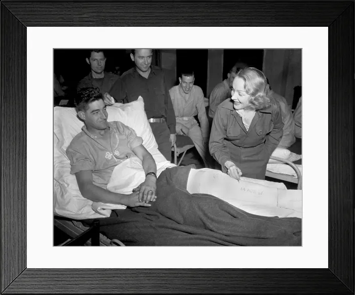Framed Print : Marlene Dietrich, autographs the cast on the leg of Tec 4 Earl McFarland of Cavider, Texas. At a U.S. hospital in Belgium, Nov. 24, 1944