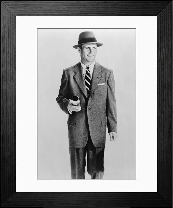 Framed Print : Male model dressed in a wearing single-breasted grey flannel suit and hat representing a businessman. 1953. (BSLOC_2010_18_73)