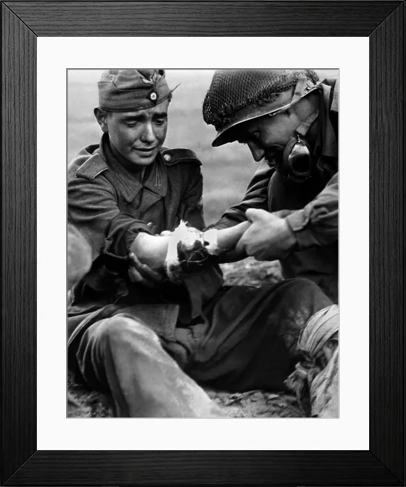 Framed Print : Teenage German POW's arm wound is examined by an older American soldier. In the last year of the World War 2, both Germany and U.S. lowered draft ages to fill ranks Framed Print : Teenage German POW's arm wound is examined by an older American soldier. In the last year of the World War 2, both Germany and U.S. lowered draft ages to fill ranks