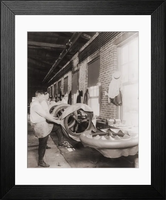 Framed Print : Workers in a tire shop applying the first ply of rubber on a handmade tires. 1916 Framed Print : Workers in a tire shop applying the first ply of rubber on a handmade tires. 1916