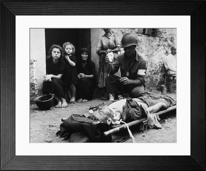 Framed Print : Wounded U.S. soldier receives blood plasma while lying on a stretcher in a street in Sicily during World War II. Behind the medic, barefoot Sicilian civilians watch. 1943 Framed Print : Wounded U.S. soldier receives blood plasma while lying on a stretcher in a street in Sicily during World War II. Behind the medic, barefoot Sicilian civilians watch. 1943
