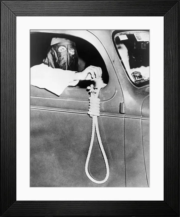 Framed Print : Masked Ku Klux Klan member, holds a noose outside a car window during a parade through an African American neighborhood of Miami on the night before a primary election in May 1939