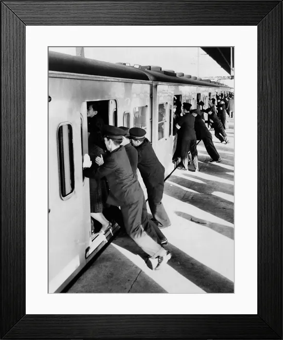Framed Print : Japanese college students employed as uniformed pushers cramming Tokyo commuters into railroad passenger cars. 1962