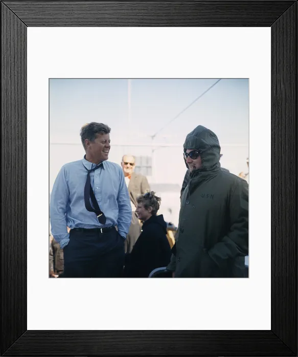 Framed Print : President Kennedy stands beside his bundled up Press Secretary, Pierre Salinger. They are watching the America's Cup Race from the Deck of the USS Joseph P. Kennedy, Jr