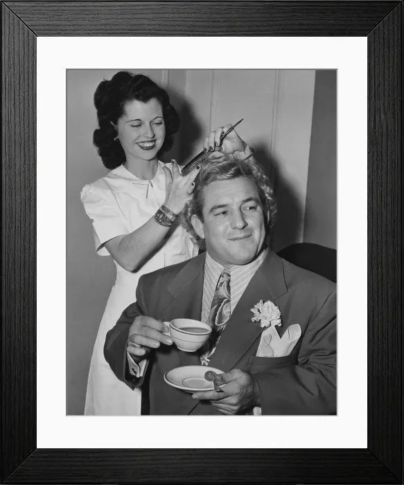 Framed Print : Wrestler Gorgeous George holding a tea cup as his hair is styled by Miss Bettie of Hollywood. Feb. 19, 1949. He appeared in the 1949 movie, ALIAS THE CHAMP. - (BSLOC_2014_17_162)