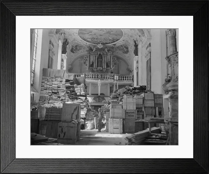 Framed Print : U.S. soldier among loot stolen from Jewish Holocaust victims, stored in church at Ellingen, Germany. The plundered items include packages, bolts of fabric, and crated paintings