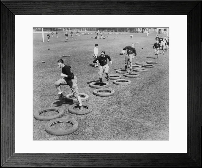 Framed Print : West Point's football squad high stepping through a maze of tires during their first practice. 1920s. (BSLOC_2015_17_127) Framed Print : West Point's football squad high stepping through a maze of tires during their first practice. 1920s. (BSLOC_2015_17_127)