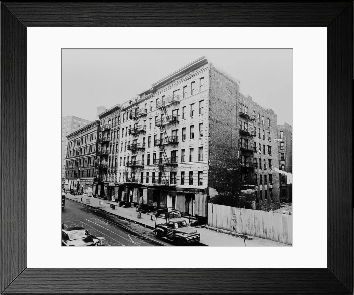 Framed Print : East Harlem street and large tenement apartment building at 311 East 100th Street in New York City. 1964