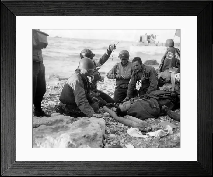 Framed Print : Medics administer a plasma transfusion to a wounded soldier on Omaha Beach on D-day. He is a survivor of a landing craft sunk in the Allied invasion of Normandy