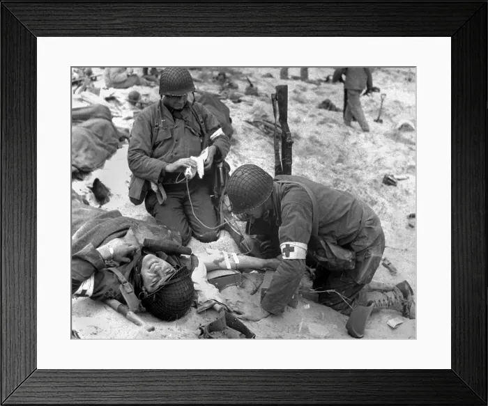 Framed Print : Medics treat a wounded U.S. soldier on D-Day. During the Normandy landings in Nazi occupied France, June 6, 1944, World War 2. (BSLOC_2014_2_37)