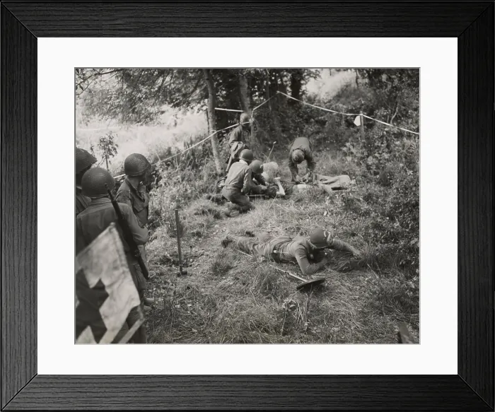Framed Print : Doctors and medics giving first aid to a combat engineer injured by a land mine. At lower right, a soldier sweeps the area for mines. June-Aug. 1944