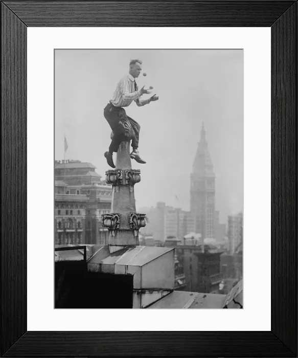Framed Print : Human Fly John Jammie Reynolds juggles while balancing atop a roof decoration in New York City