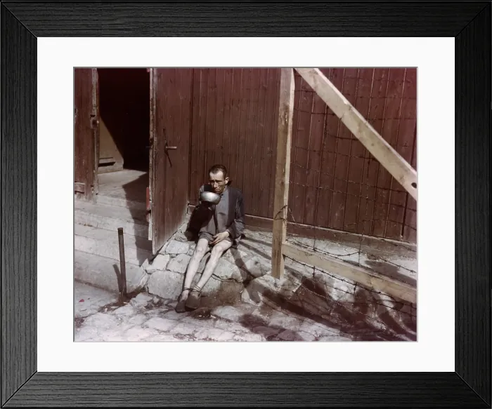 Framed Print : An emaciated survivor drinking from a metal bowl at Buchenwald concentration camp. Photo was taken after the camp was liberated by the 3rd U.S. Army