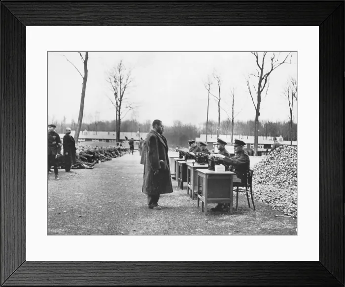 Framed Print : Gestapo officials recording data on incoming prisoners at a German concentration camp. Many others are seated on the ground (left). Ca. 1939-1945. (BSLOC_2014_4_2) Framed Print : Gestapo officials recording data on incoming prisoners at a German concentration camp. Many others are seated on the ground (left). Ca. 1939-1945. (BSLOC_2014_4_2)