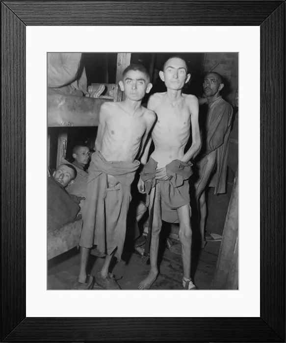 Framed Print : Jewish inmates of the Amphing concentration camp after liberation by U.S. Army. Suffering from starvation and barely clothed, two men stand in barracks with other prisoners