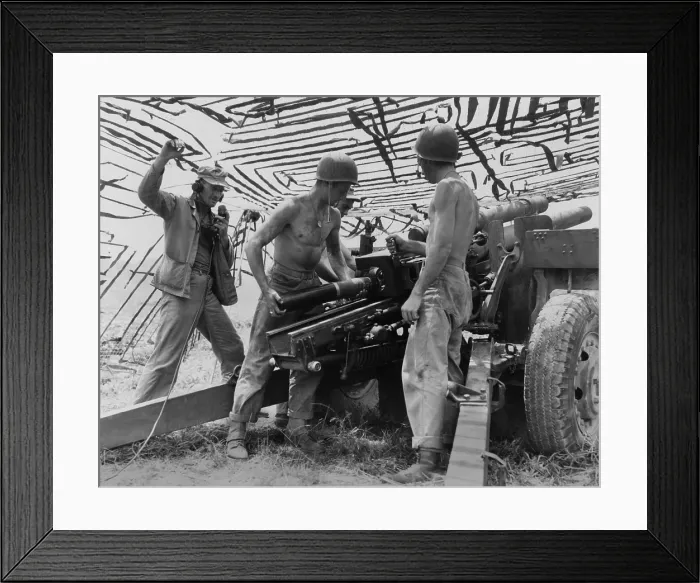Framed Print : Four soldiers man U.S. Army 105 mm. artillery under a camouflage net in South Korea in the second month of the Korean War. U.S