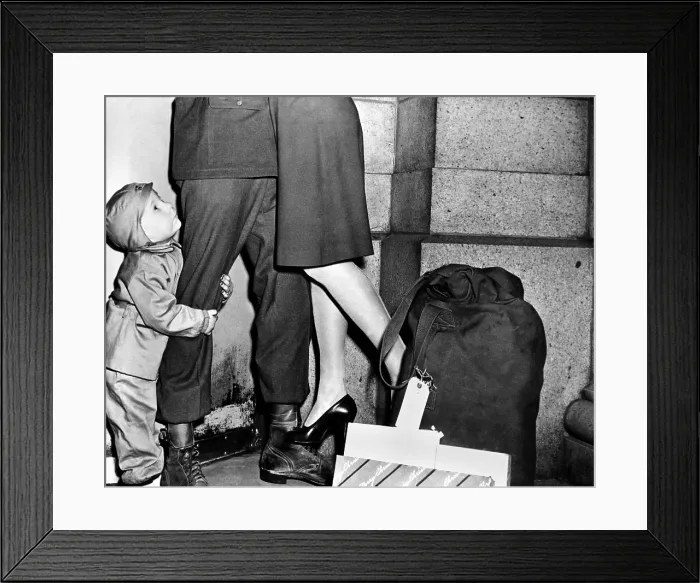 Framed Print : A youngster, clutching his soldier father's leg has lost his parents attention