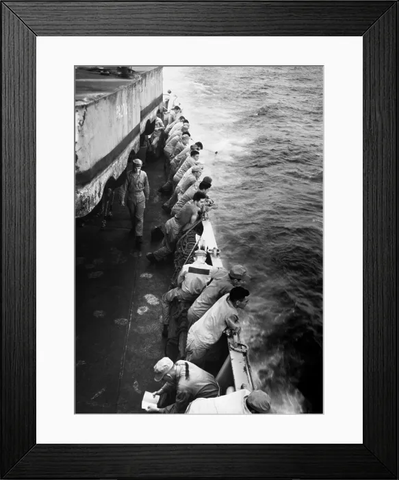 Framed Print : U.S. Marines stand along the rail of the USS Clymer taking them to Korea in late July, 1950. To the aft a Marine is washing his dungarees by dragging them along behind the ship Framed Print : U.S. Marines stand along the rail of the USS Clymer taking them to Korea in late July, 1950. To the aft a Marine is washing his dungarees by dragging them along behind the ship