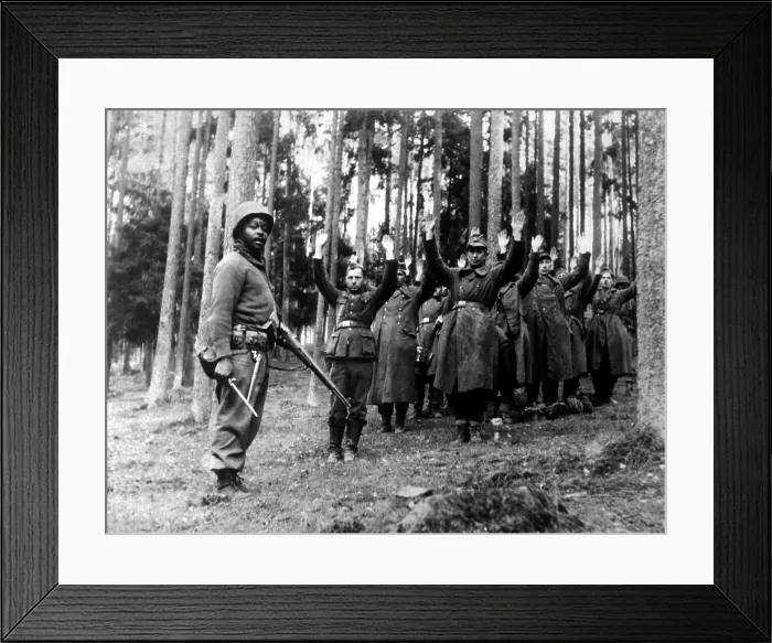 Framed Print : An African American soldier of the stands guard over a group of Nazi prisoners. The Germans were captured in the surrounding forest by the U.S Framed Print : An African American soldier of the stands guard over a group of Nazi prisoners. The Germans were captured in the surrounding forest by the U.S