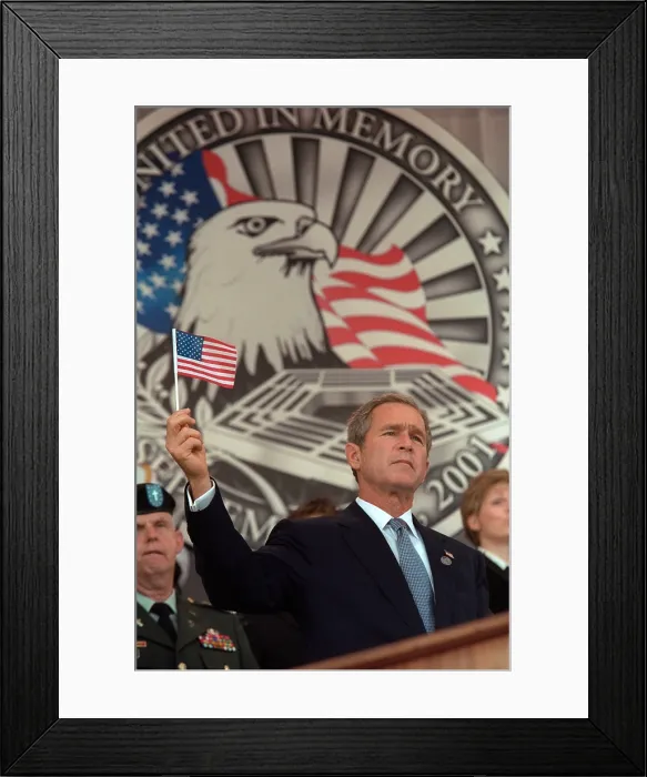 Framed Print : President George W. Bush at Remembrance Service for the 9-11 victims at the Pentagon. Behind Bush 43 is an elaborate backdrop with an eagle and he holds up a small American flag