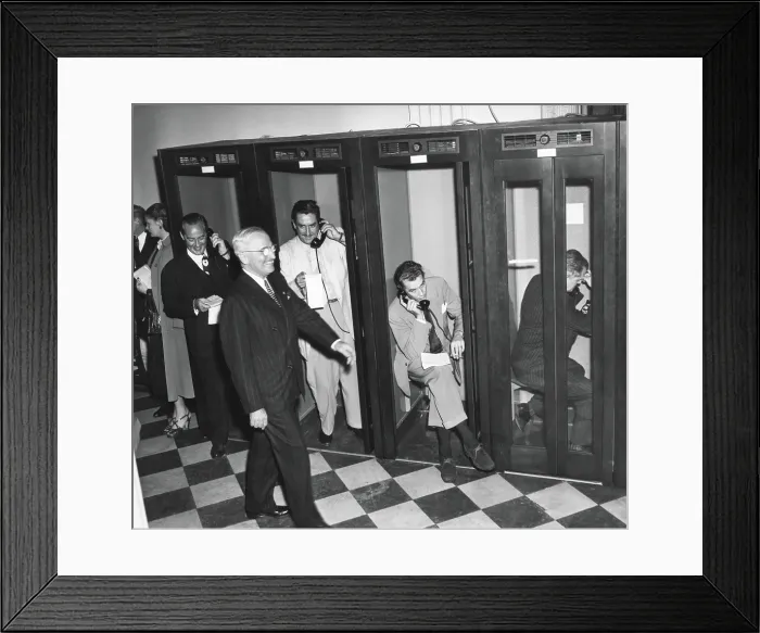 Framed Print : President Harry Truman walks past reporters in the telephone booths the Old State Department Building