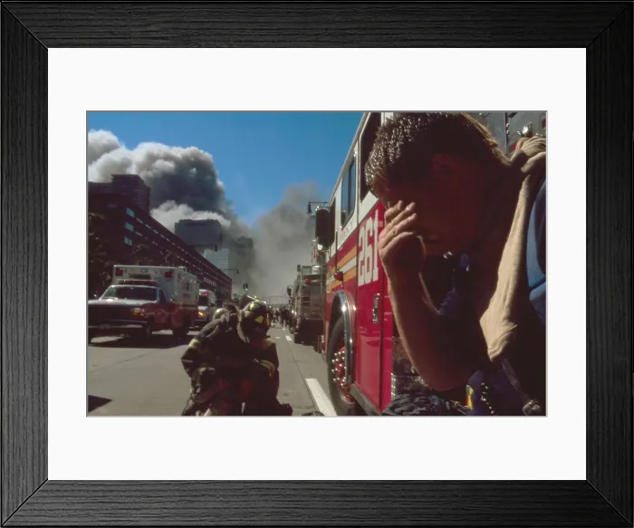 Framed Print : New York City fire fighter north of the collapsed Twin Towers. Behind him are other firemen, fire trucks, and rescue vehicles