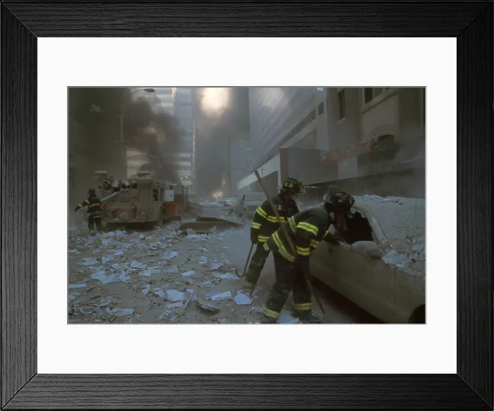 Framed Print : NYC firemen checking a car on Barclay Street after the 9-11 terrorist attack on World Trade Center. In the mid-ground fireman pulls a water hose from fire truck