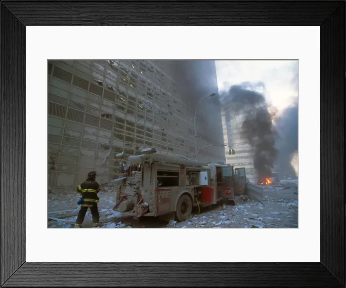 Framed Print : NYC fireman pulling water hose from fire truck after the 9-11 terrorist attack on World Trade Center. View is toward West Broadway and a burning car. (BSLOC_2015_2_54)
