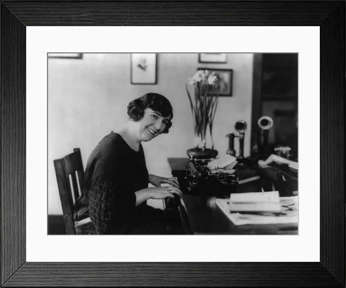 Framed Print : Smiling woman office worker seated at typewriter, in 1923. (BSLOC_2015_16_220)