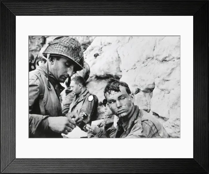 Framed Print : U.S. soldier who was injured during landing on Normandy beachhead, on D-Day plus 1. A medic bandages his hand. The marks on his face came from water spray while landing