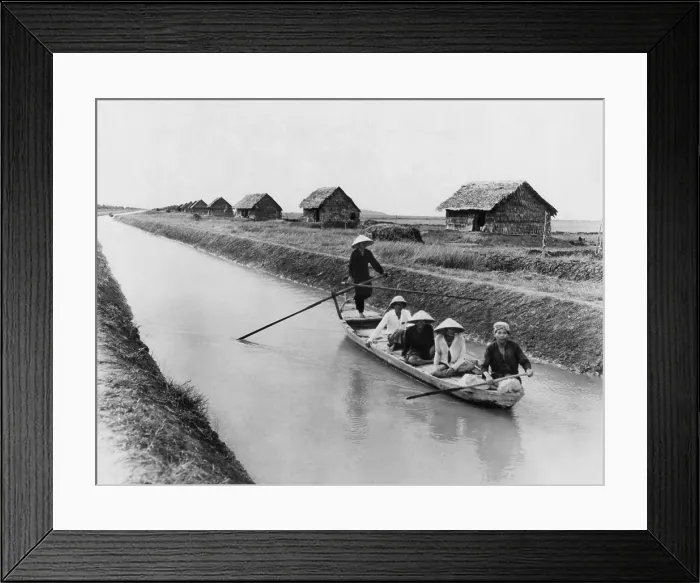 Framed Print : Vietnamese men in a sampan on a canal near straw dwellings that house refugees from North Vietnam. 1956. LC-DIG-ppmsca-09168