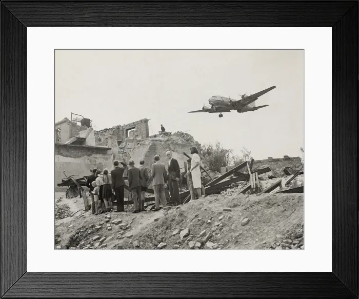 Framed Print : West Berliners gathered near war ruins in Berlin watch a U.S. Air Force transport plane