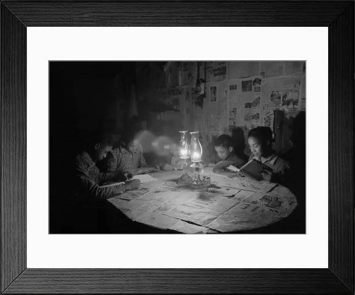 Framed Print : African American children reading by kerosene lantern light at a diner table, Depew, Oklahoma, Feb. 1940. The table and walls are covered with newspapers. Photo by Russell Lee