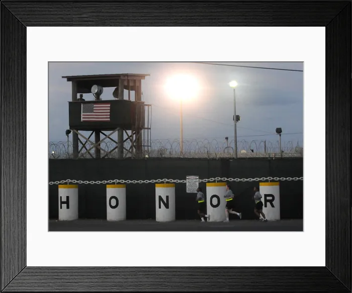 Framed Print : Female Military Police jog past a guard tower with a prominent American Flag and barriers that spell out HONOR at Camp Delta the military prison in Naval Base Guantanamo Bay Cuba Framed Print : Female Military Police jog past a guard tower with a prominent American Flag and barriers that spell out HONOR at Camp Delta the military prison in Naval Base Guantanamo Bay Cuba
