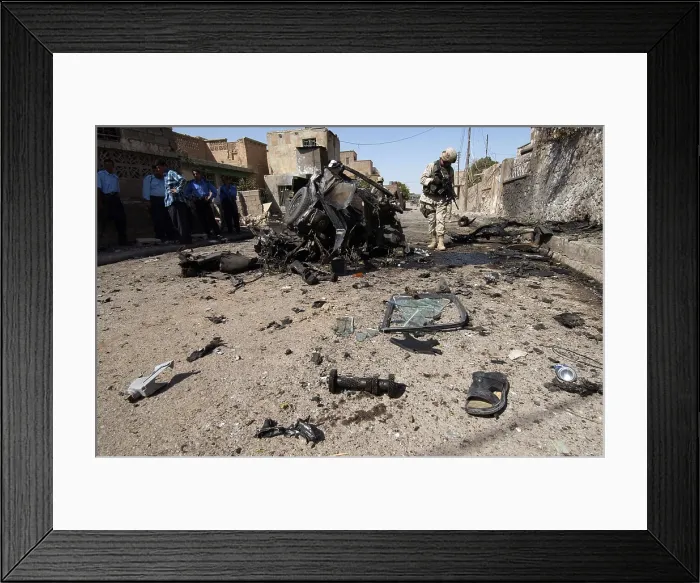 Framed Print : US soldier inspects the area around a suicide bomber's vehicle in Tuz Iraq. The bomber killed himself injured four civilians and three Iraqi Police Officers. June 17 2005